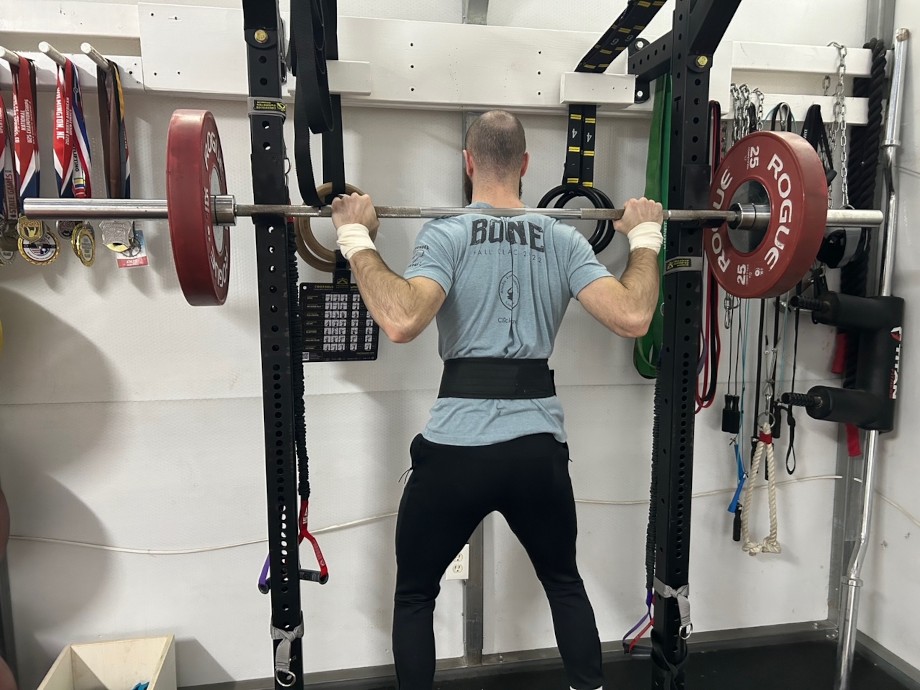 Beginner home gym setup with power rack, barbell, and weightlifting equipment