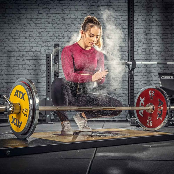 Athlete applying weightlifting chalk before a barbell deadlift in a home gym