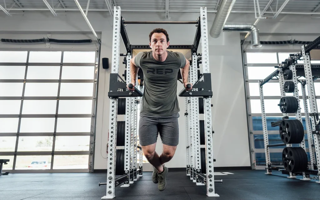 Person performing dips on power rack dip attachment