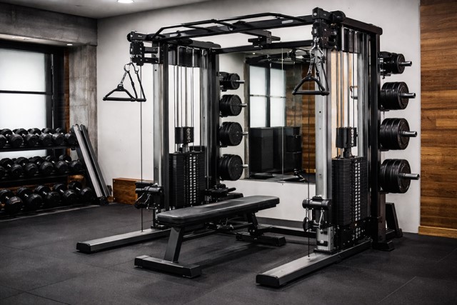 Home gym setup with power rack, barbell, bench, and dumbbells in a clean garage gym space