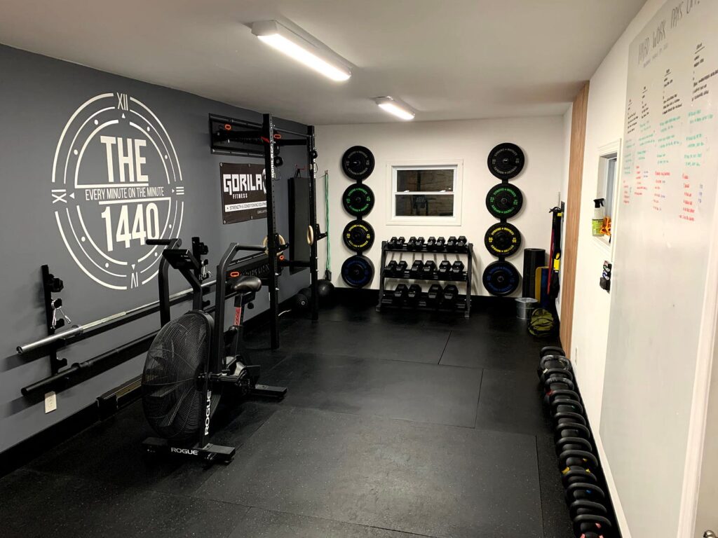 wall mounted storage system in a garage gym holding barbells, weight plates, and accessories in an organized layout