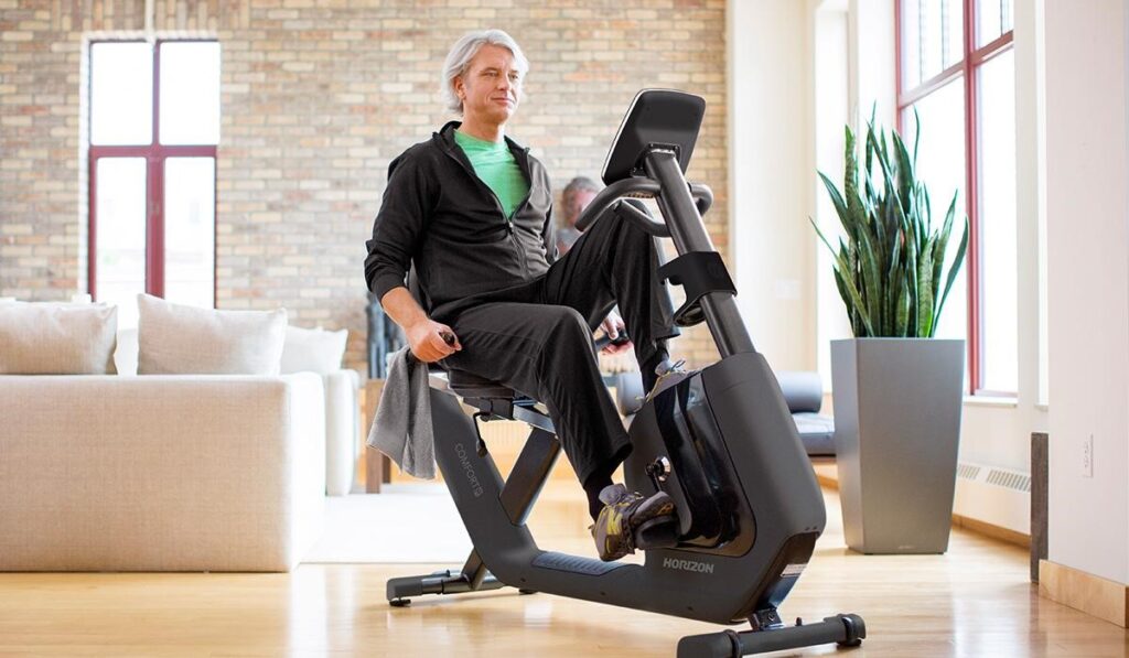 Person using a recumbent exercise bike in a bright home gym setting