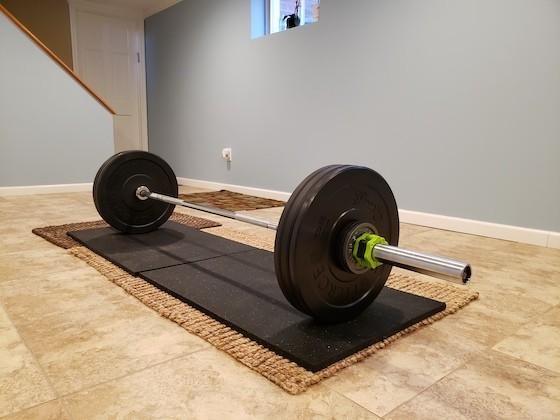 Barbell on shock absorbing lifting platform with rubber flooring in home gym