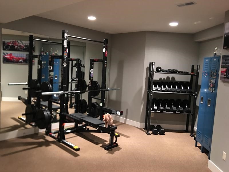 Beginner home gym setup in a clean garage space with adjustable bench, dumbbells, kettlebell, resistance bands, and open floor area for progression