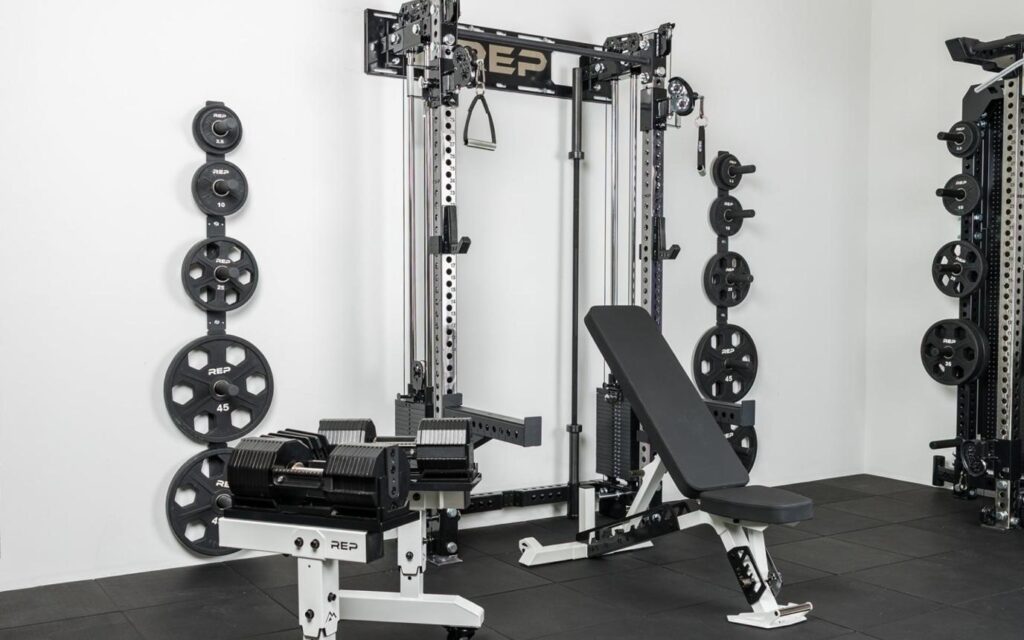 Home gym layout showing a staged fitness setup with bench, dumbbells, suspension trainer, kettlebell, and training mat in a functional workout area